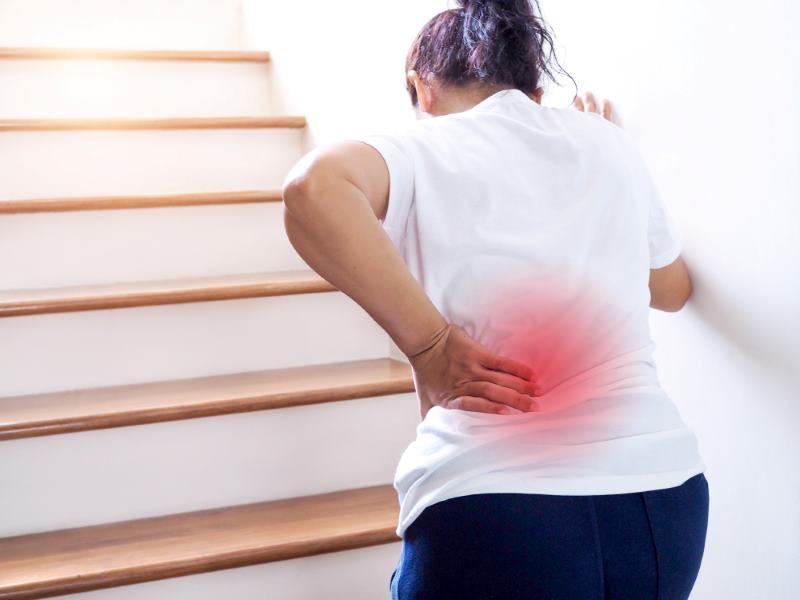 Woman Suffering From Low Back Pain When Walking Up Stairs